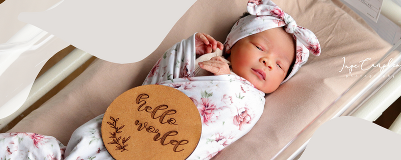 Sleeping baby wrapped in Tiger Lily Swaddle with a matching beanie