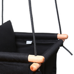 Black baby swing with grey ropes, and wooden dowels.